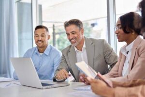 Cheerful employees gather around a laptop during a meeting