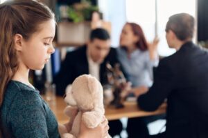 A young girl cuddles her teddy as her parents argue over divorce