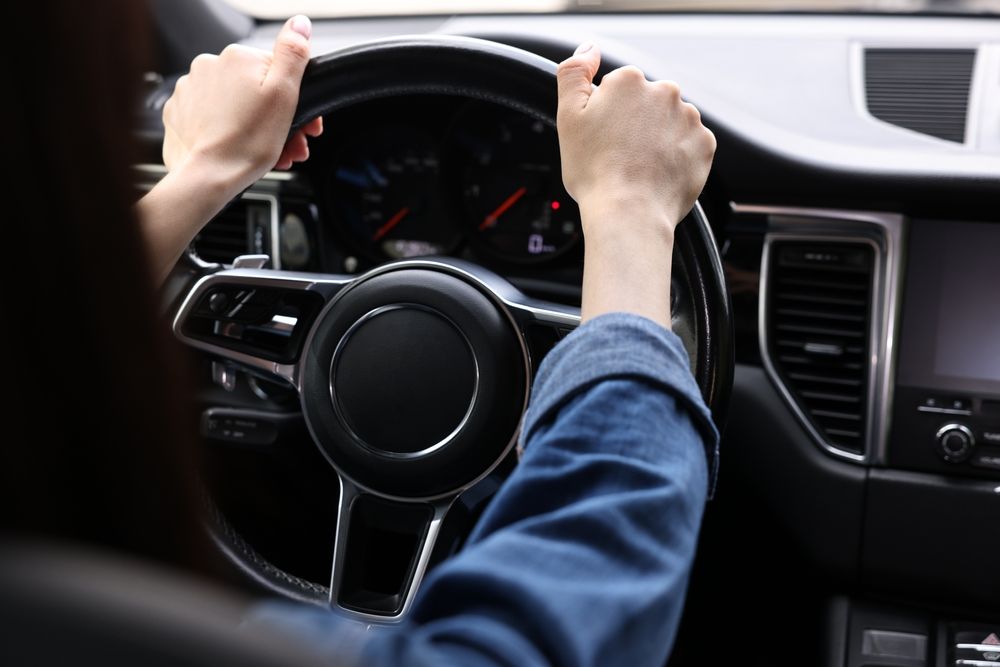 A woman holds a steering wheel tightly whilst driving